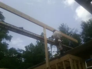 Carpenter setting a ridge beam over a new addition frame — Ice Dam Removal by Roofing Brothers in Cramerton