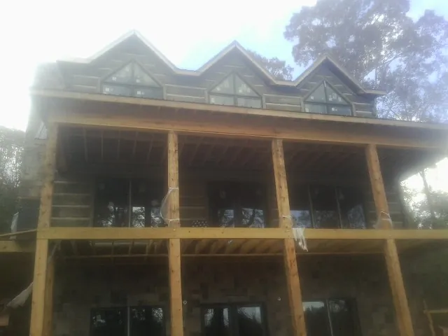 Dormers and porch framing on a large log home under construction — Roof Coating work by our crew in Cramerton