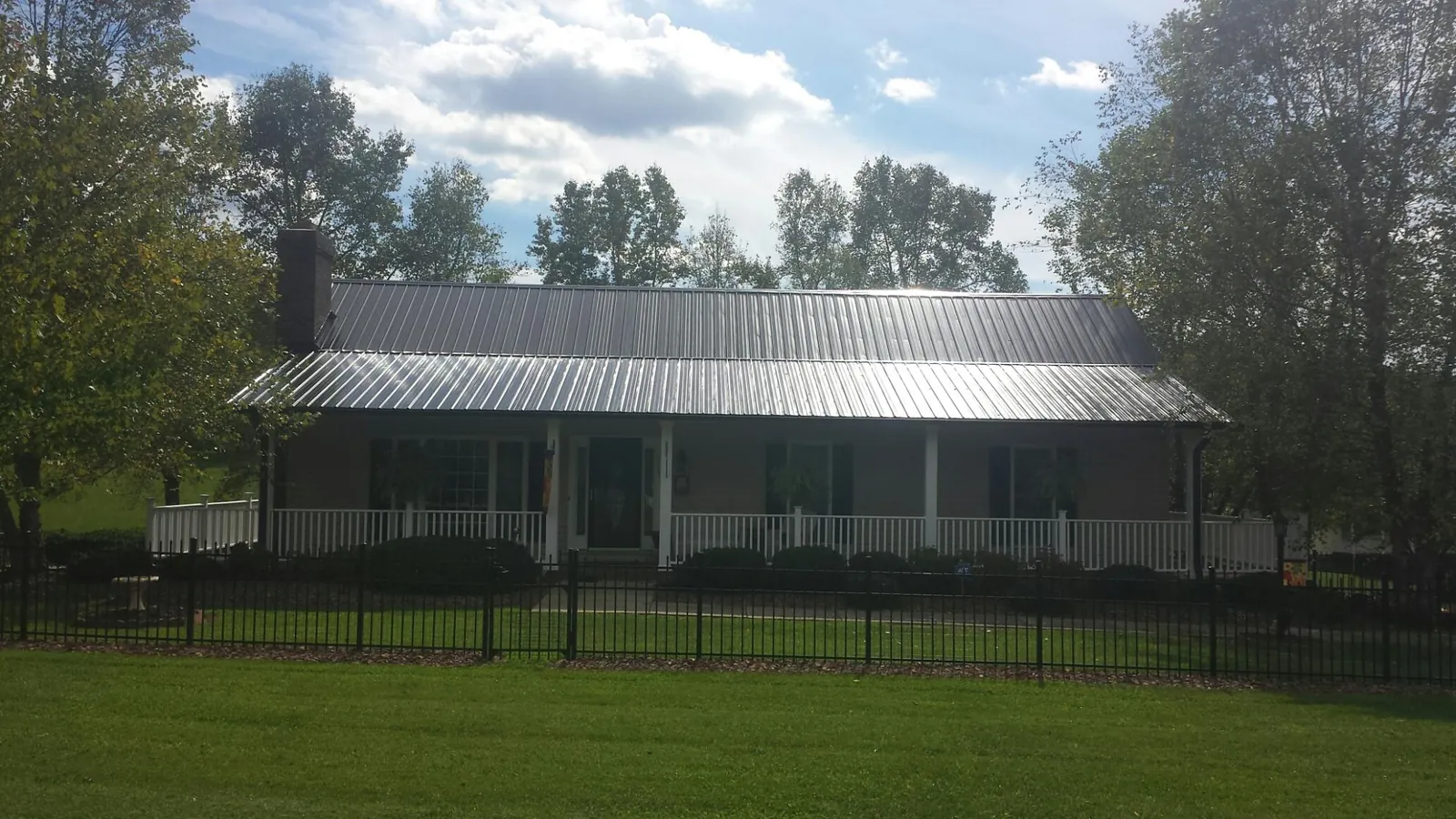 Gray metal roof on a brick ranch with a full width front porch — Gutter Guard Installation work by our crew in Cramerton