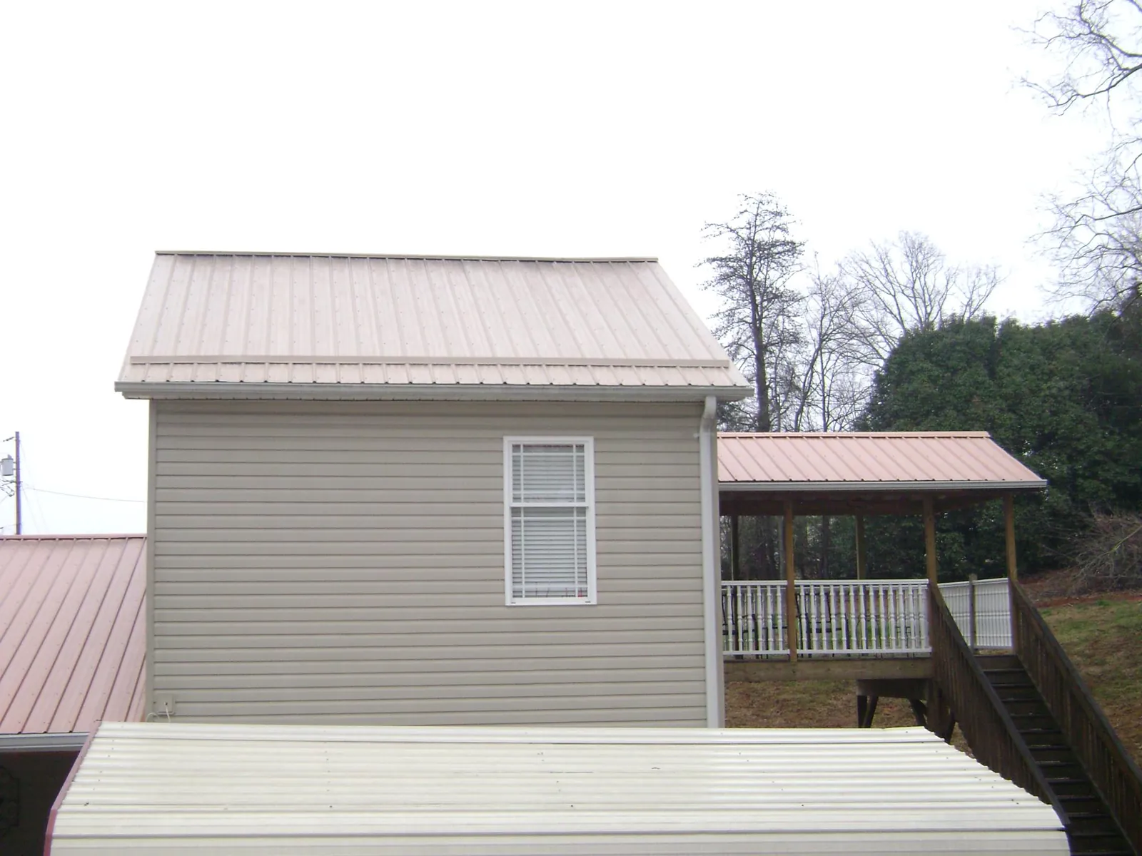 Tan metal roofs on a two story addition and attached porch, from a Roof Replacement job in Cramerton