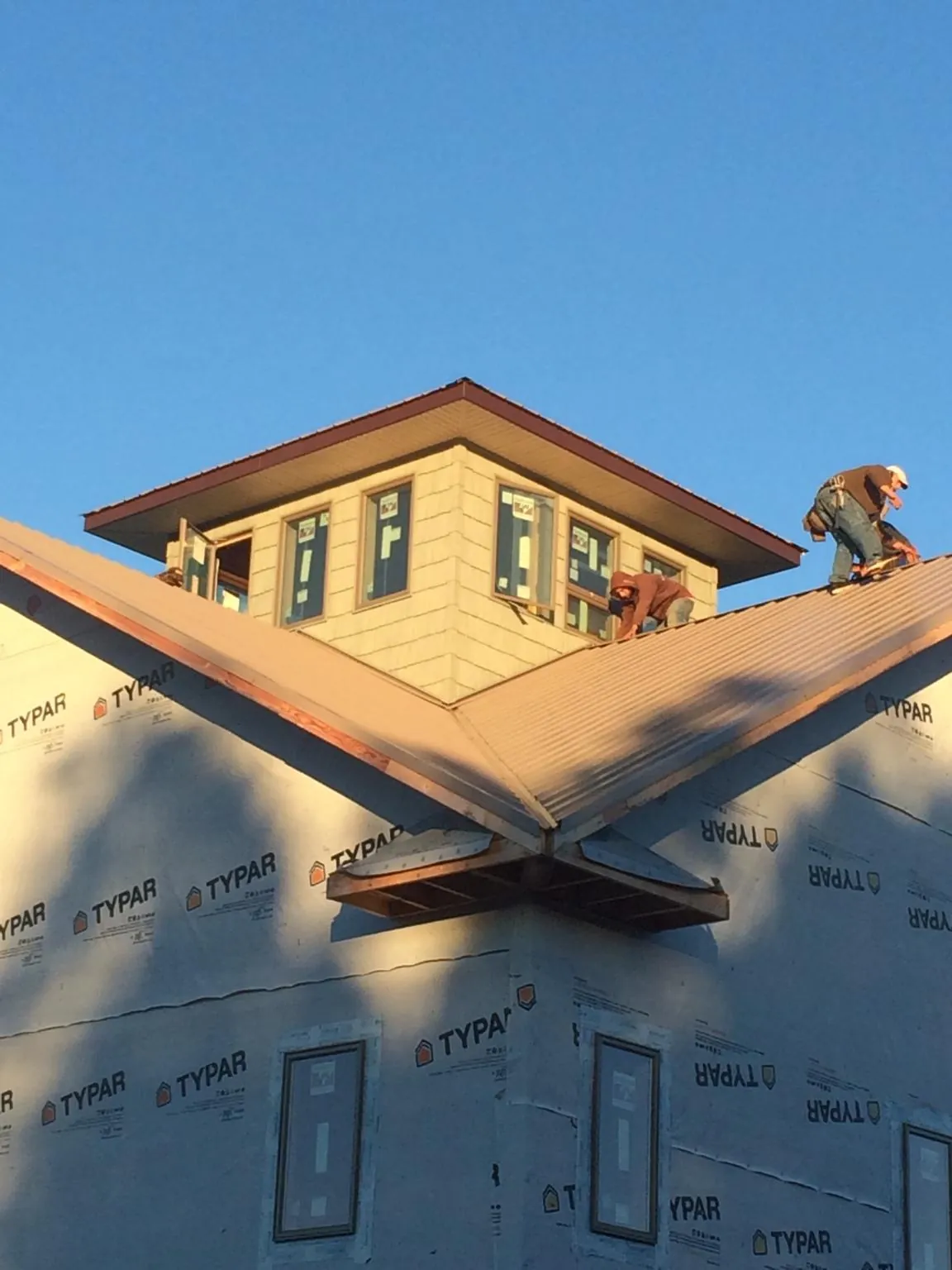 Roofers working around a rooftop cupola on a new metal roof at sunset — Roof Waterproofing in Cramerton by Roofing Brothers